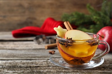 Photo of Hot mulled cider on wooden table, space for text