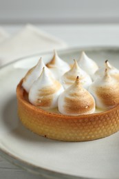 Tartlet with meringue on white table, closeup. Delicious dessert