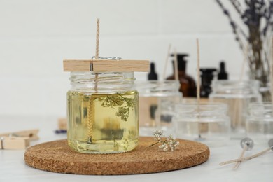 Photo of Glass jar with melted wax on white table, space for text. Handmade candle