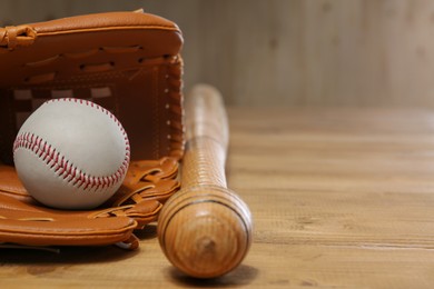 Photo of Baseball glove, bat and ball on wooden table, closeup. Space for text