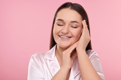 Photo of Smiling woman with dental braces on pink background