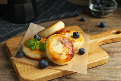 Photo of Delicious cottage cheese pancakes with blueberries and mint on wooden table