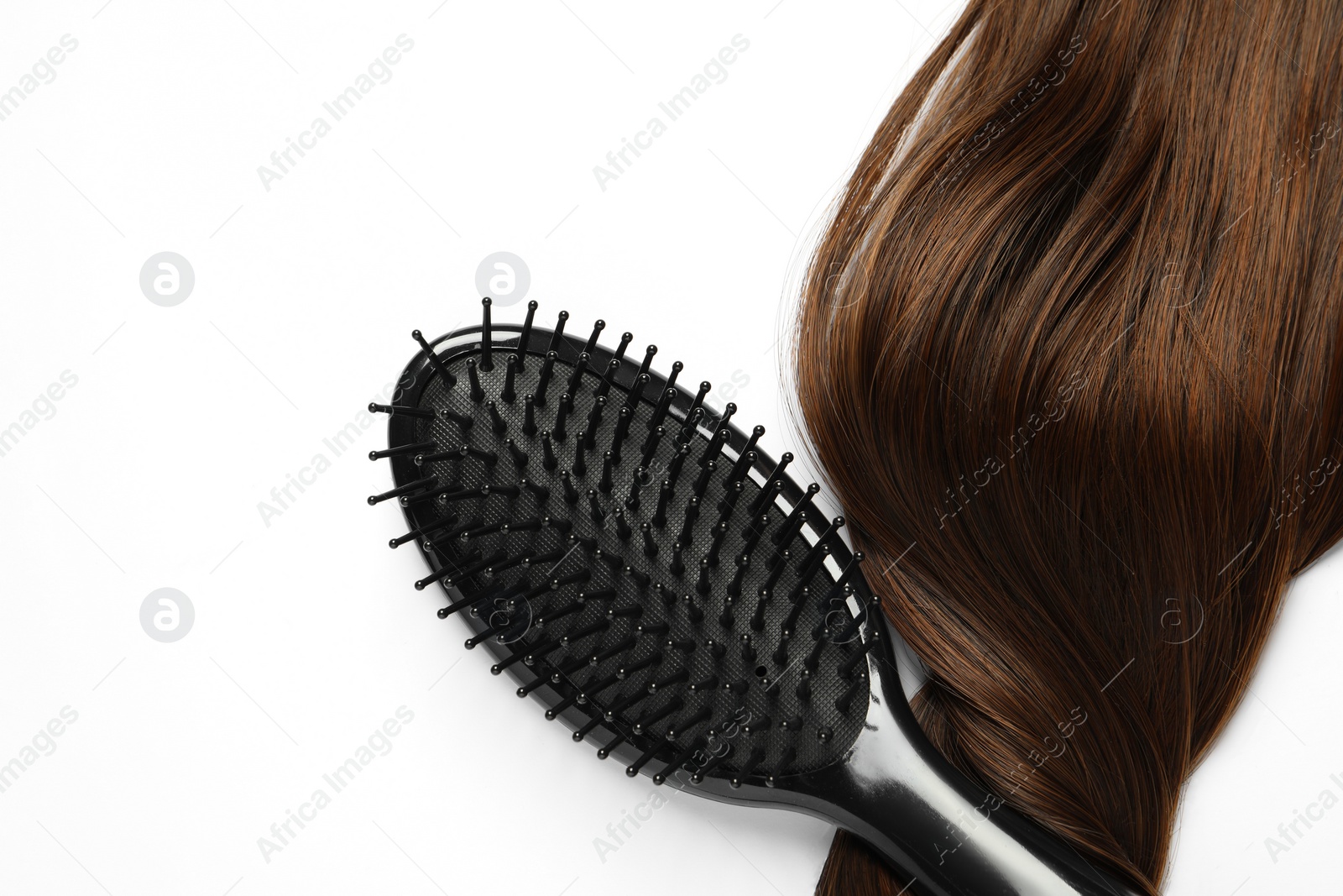 Photo of Stylish brush with brown hair strand on white background, top view