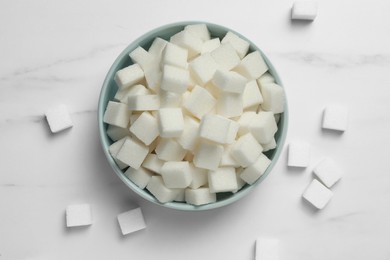 Photo of Bowl of white sugar cubes on marble table, flat lay