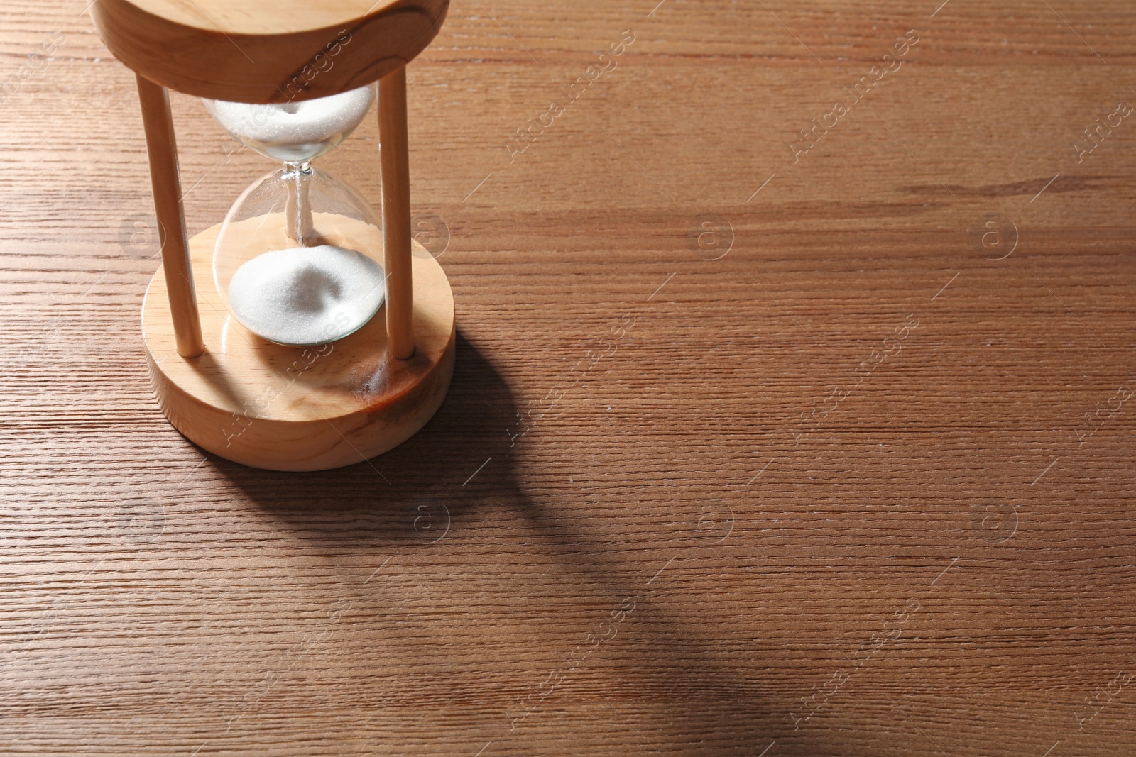 Photo of Hourglass with flowing sand on wooden background. Time management