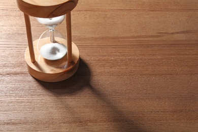 Photo of Hourglass with flowing sand on wooden background. Time management