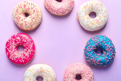 Photo of Frame made of delicious doughnuts on color background, top view