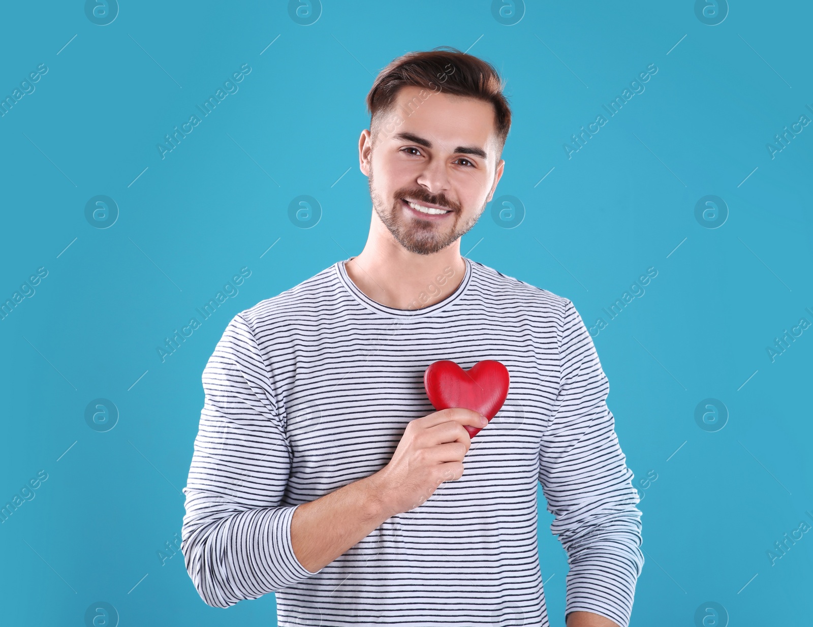 Photo of Man holding decorative heart on color background