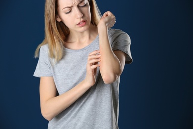 Woman scratching forearm on color background. Allergy symptom