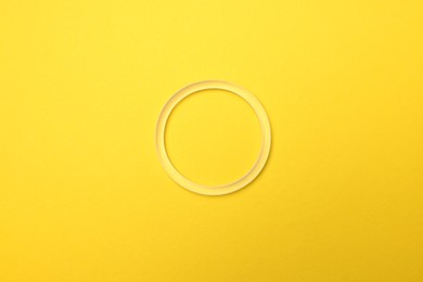 Photo of Diaphragm vaginal contraceptive ring on light yellow background, top view