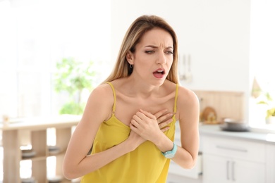 Young woman having heart attack indoors