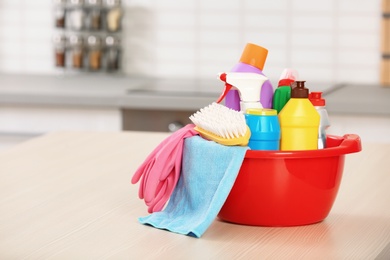 Photo of Set of cleaning supplies on table in kitchen. Space for text