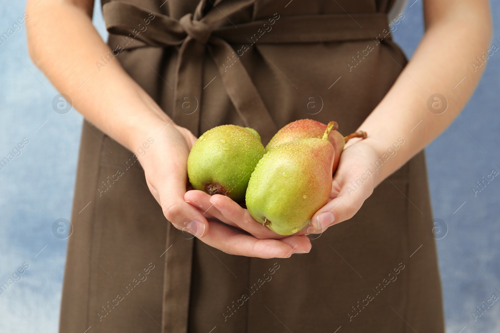 Photo of Woman in apron with ripe pears on color background, closeup