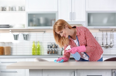 Woman cleaning table with rag in kitchen