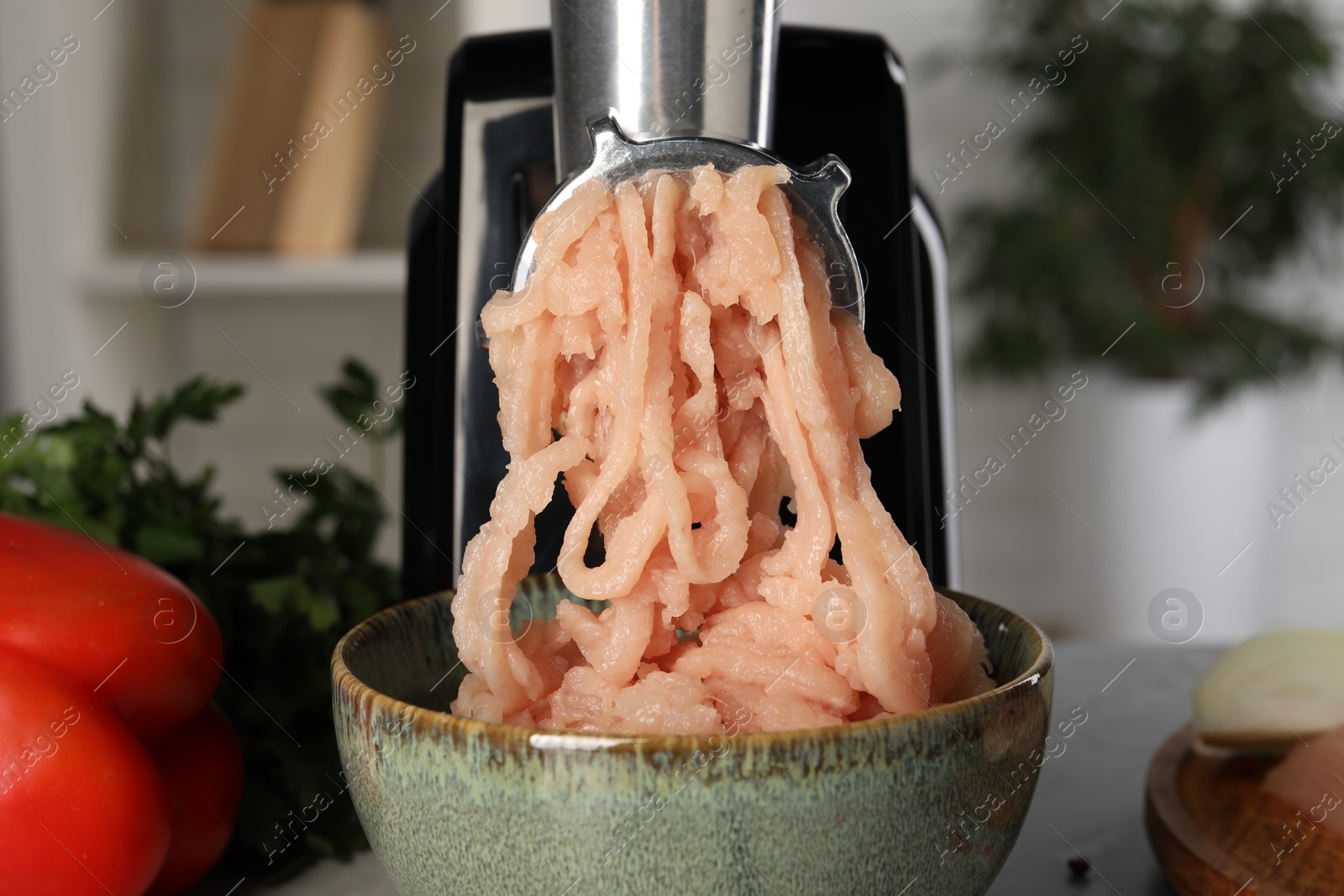 Photo of Electric meat grinder with chicken mince and products on table indoors, closeup