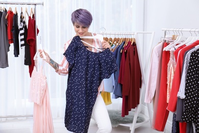 Photo of Beautiful young stylist choosing clothes in studio