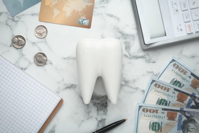 Photo of Flat lay composition with ceramic model of tooth and money on white marble table. Expensive treatment