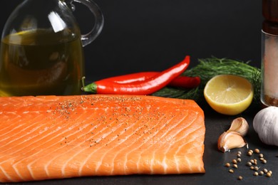 Photo of Fresh raw salmon and ingredients for marinade on black table