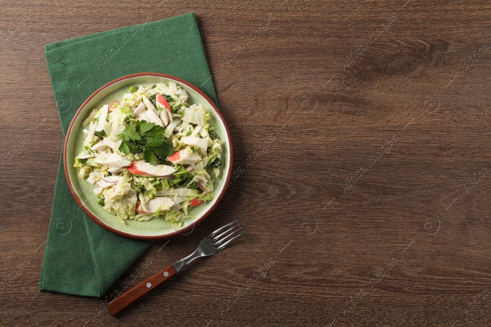 Photo of Delicious salad with Chinese cabbage, crab sticks and parsley on wooden table, top view. Space for text