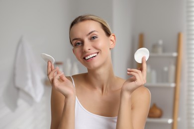 Photo of Removing makeup. Smiling woman with cotton pads indoors