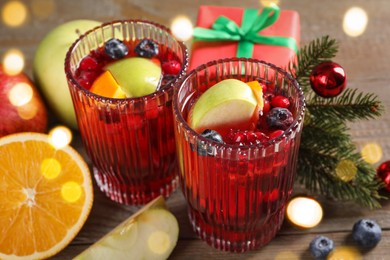 Aromatic Sangria drink in glasses, ingredients and Christmas decor on wooden table