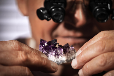 Professional jeweler working with beautiful amethyst, closeup