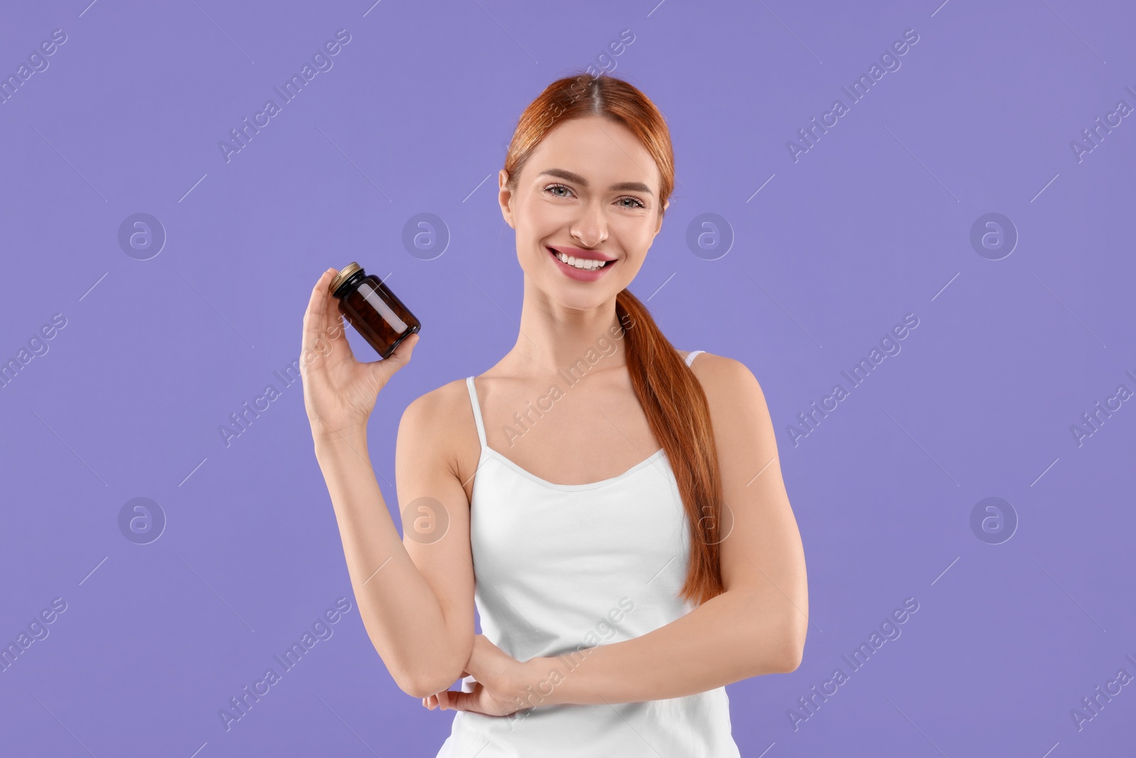 Photo of Happy young woman with bottle of pills on purple background. Weight loss