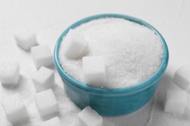 Photo of Different types of sugar in bowl on white table, closeup