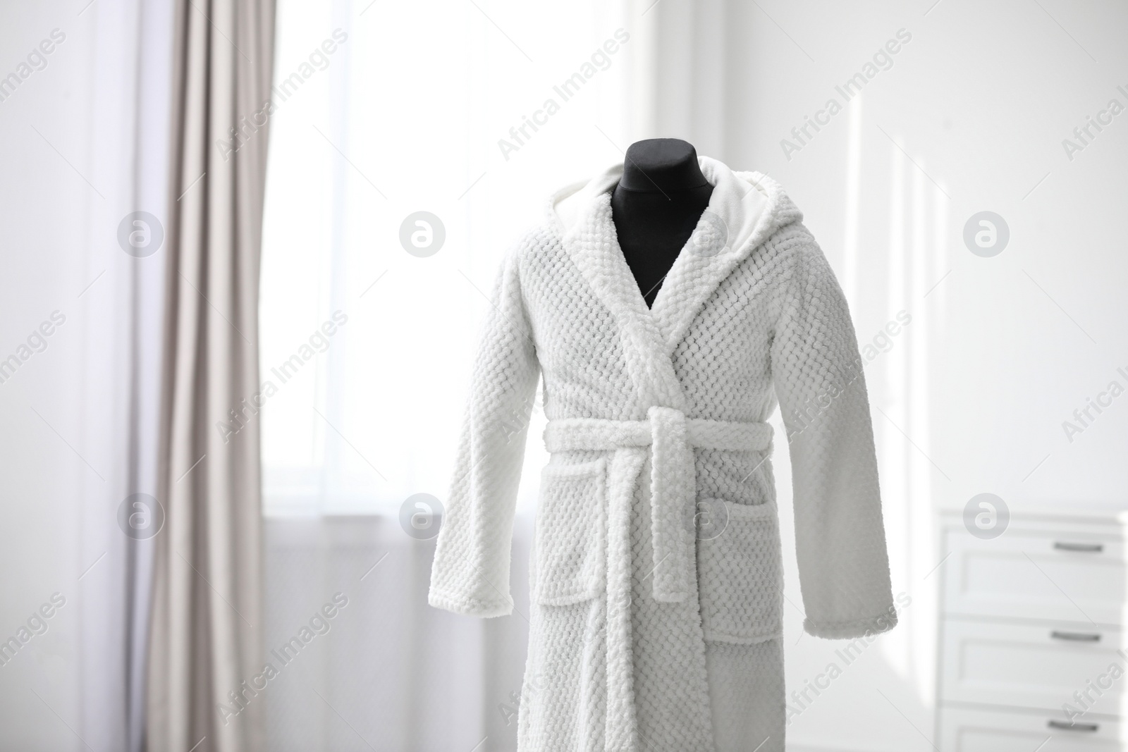 Photo of Soft comfortable bathrobe on mannequin in room