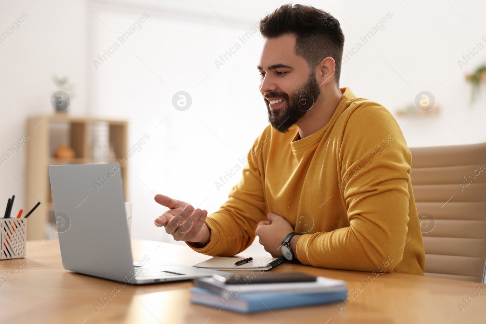 Photo of Young man using video chat during webinar at table in room