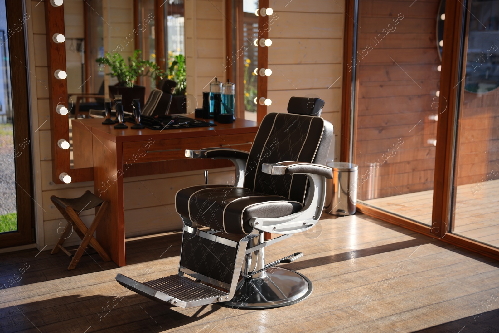Photo of Stylish hairdresser's workplace with professional armchair and large mirror in barbershop. Interior design