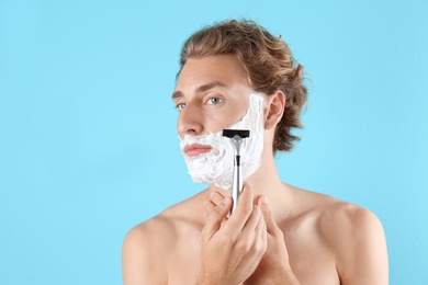 Photo of Handsome young man shaving on color background