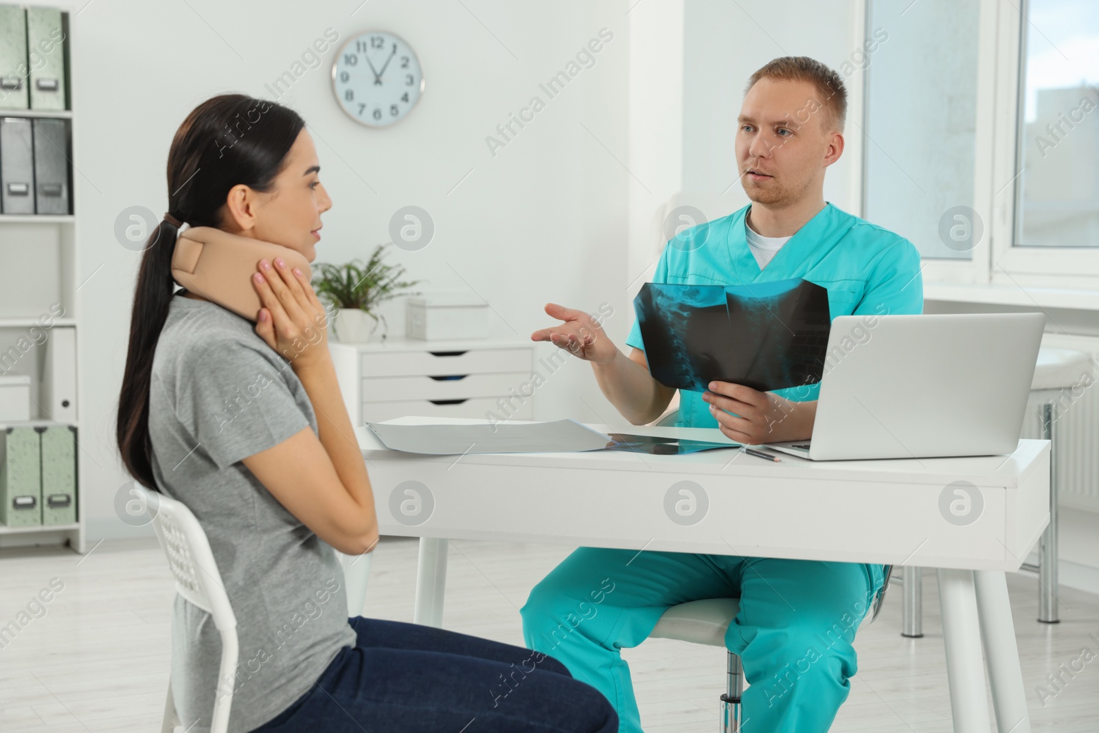 Photo of Doctor with neck MRI image consulting patient in clinic