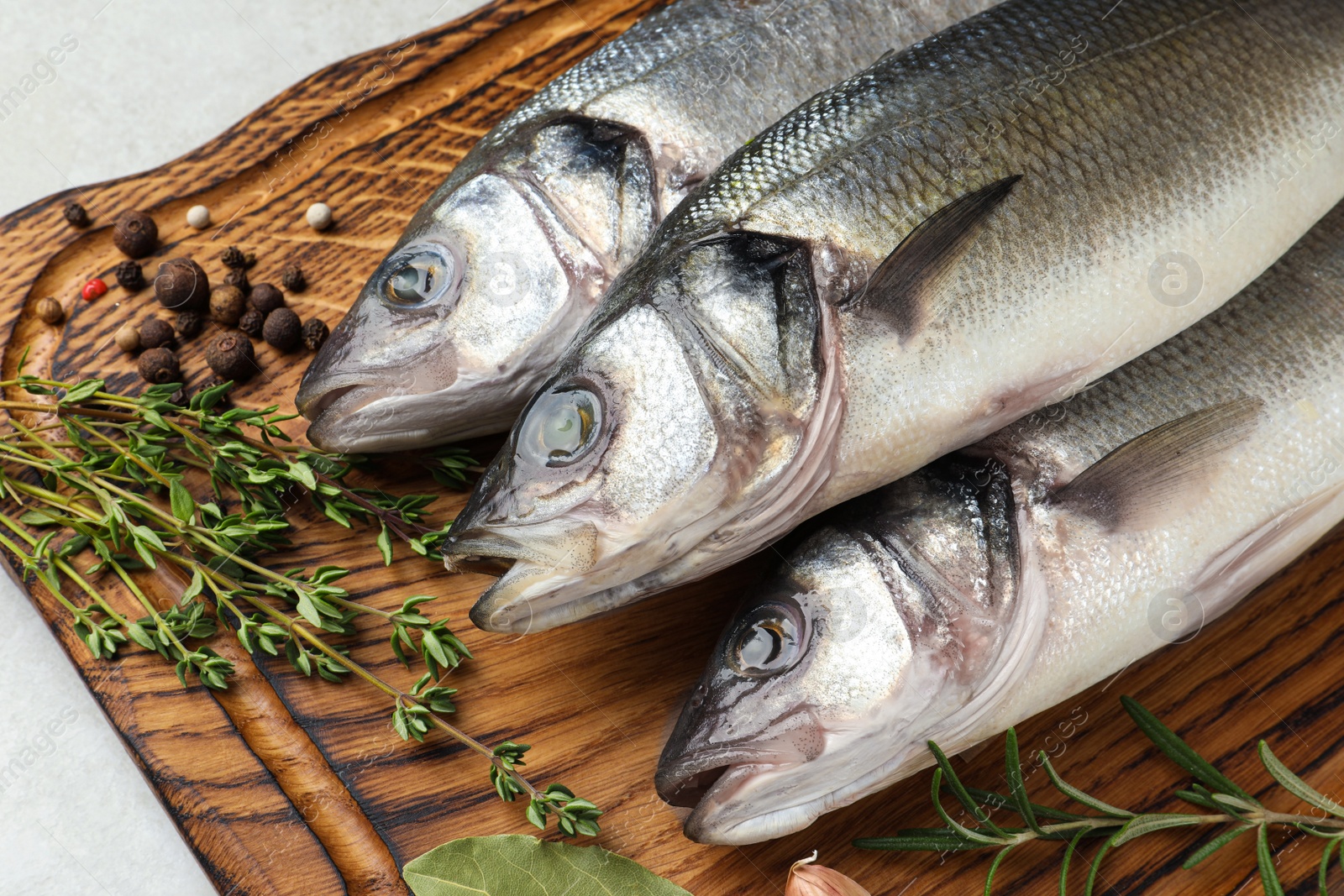 Photo of Tasty sea bass fish with spices on grey textured table, closeup