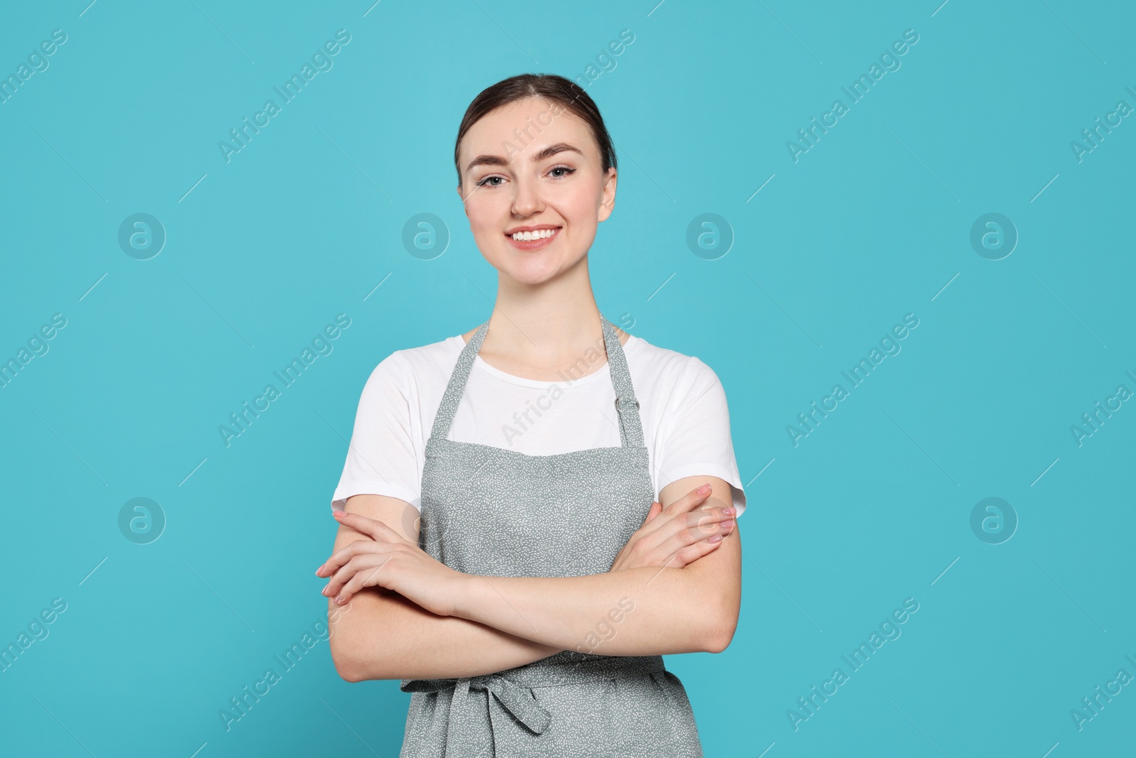 Photo of Beautiful young woman in clean apron with pattern on light blue background