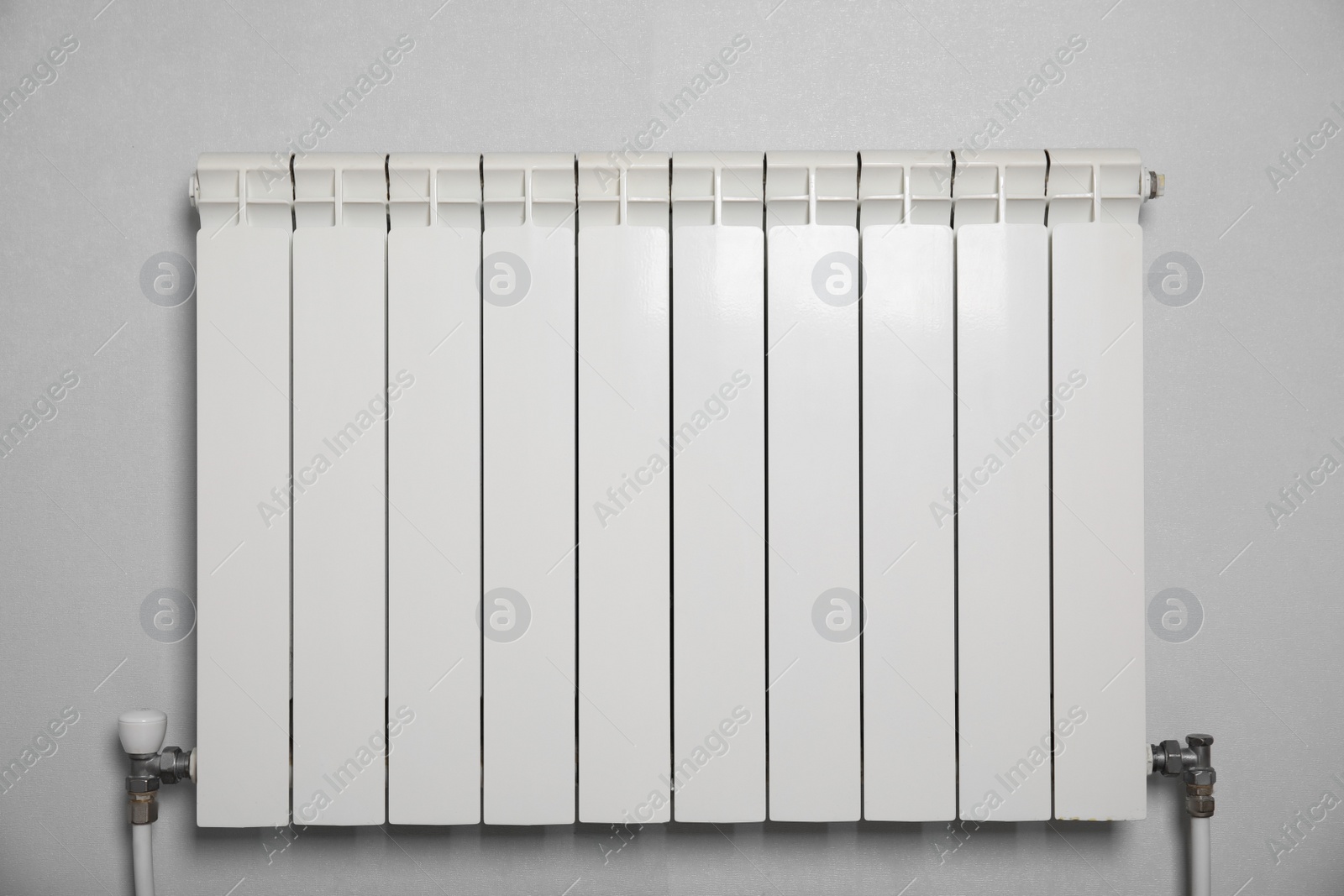 Photo of Modern heating radiator on light wall indoors