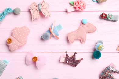 Photo of Cute hair clips on pink wooden table, flat lay