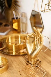 Photo of Composition with gold accessories and jewelry on dressing table near white wall