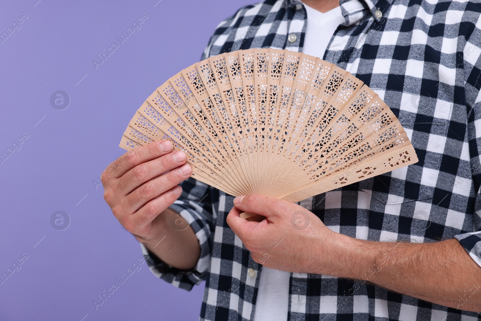 Photo of Man holding hand fan on purple background, closeup