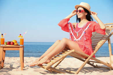 Beautiful woman in red dress resting on beach