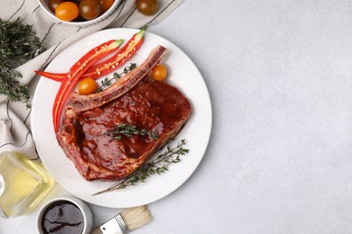 Photo of Raw marinated meat with thyme, chili pepper and basting brush on light table, flat lay. Space for text