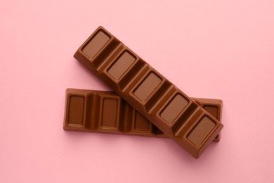 Delicious chocolate bars on pink background, flat lay