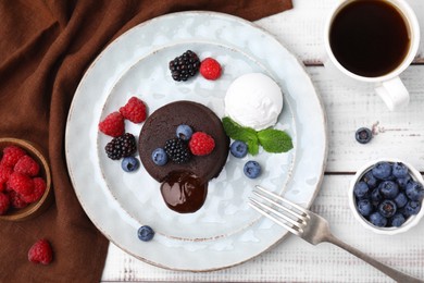 Photo of Delicious chocolate fondant served with fresh berries and ice cream on white wooden table, flat lay