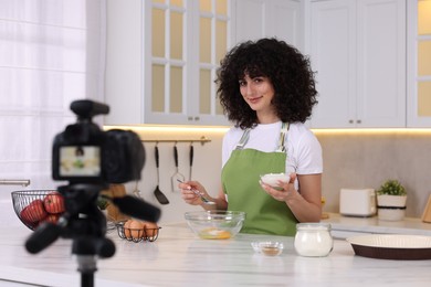 Photo of Food blogger cooking while recording video in kitchen