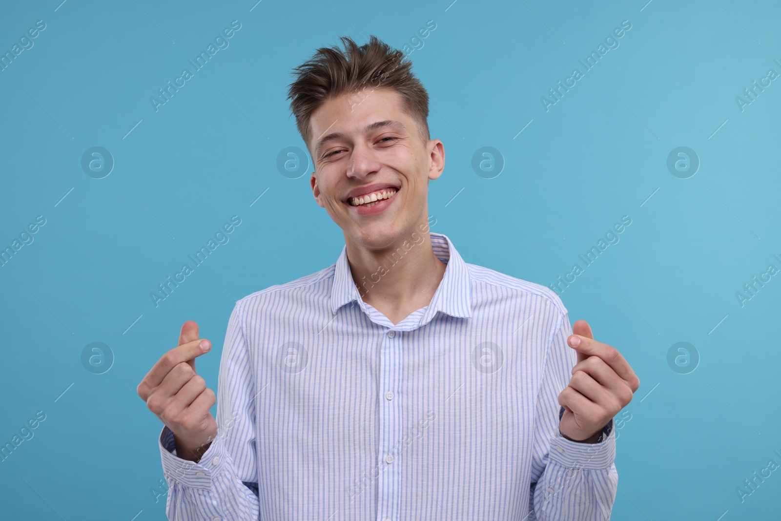 Photo of Happy man showing money gesture on light blue background