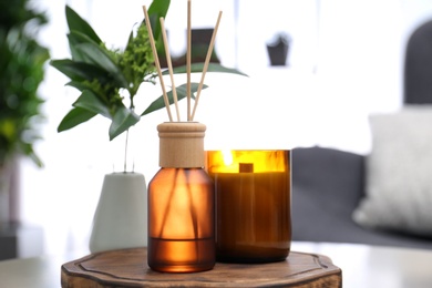 Photo of Reed air freshener and candle on table indoors