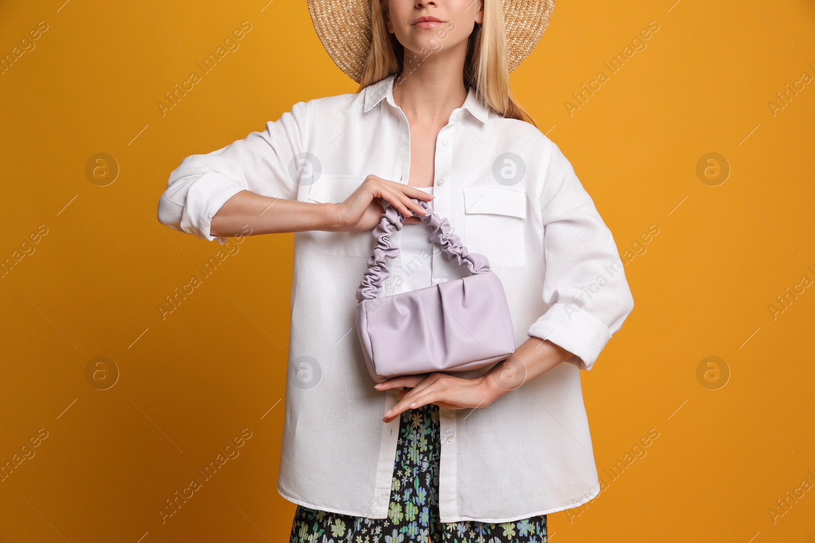 Photo of Stylish woman with trendy baguette bag on yellow background, closeup