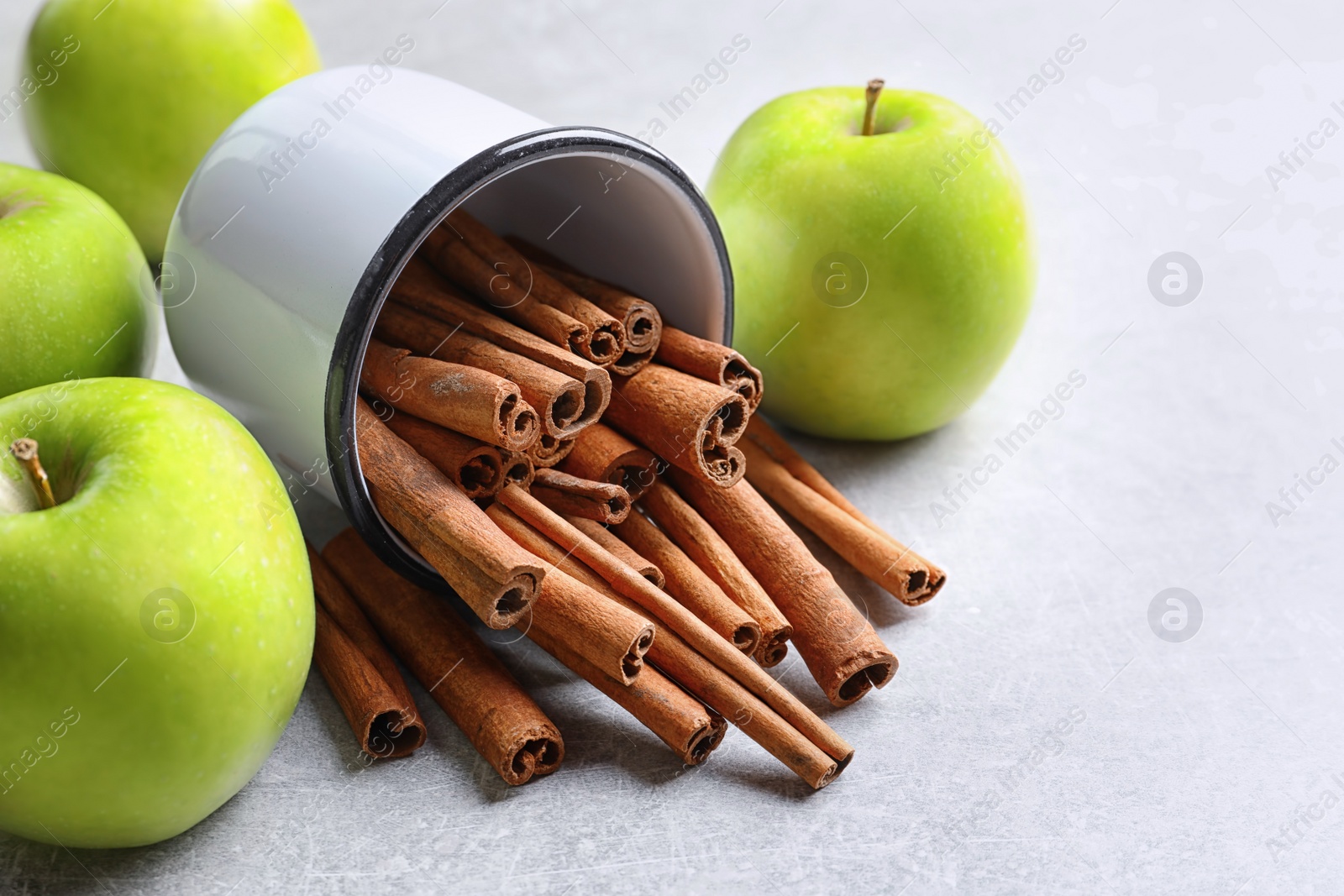 Photo of Fresh apples and mug with cinnamon sticks on table