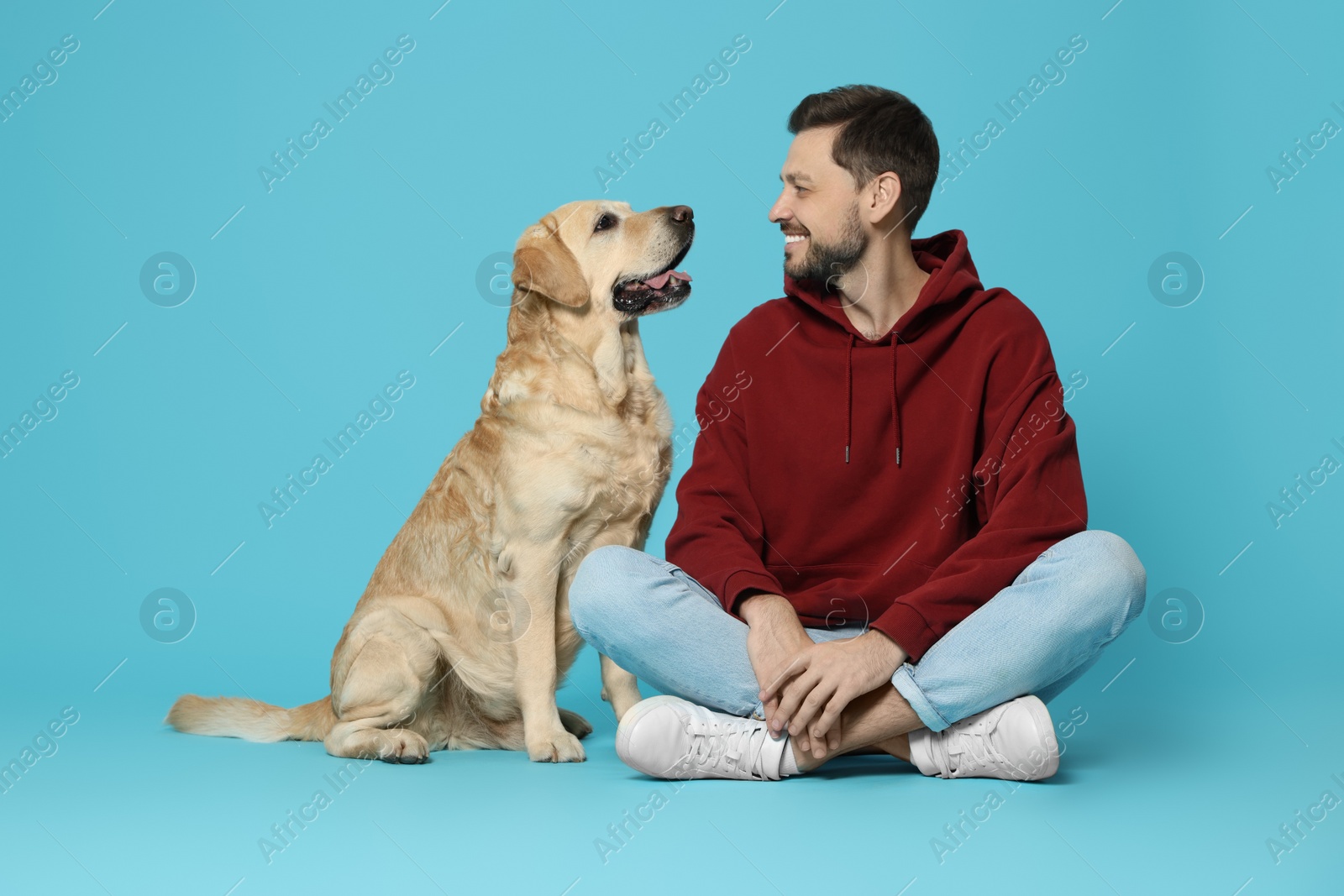 Photo of Happy man with his cute Labrador Retriever on turquoise background