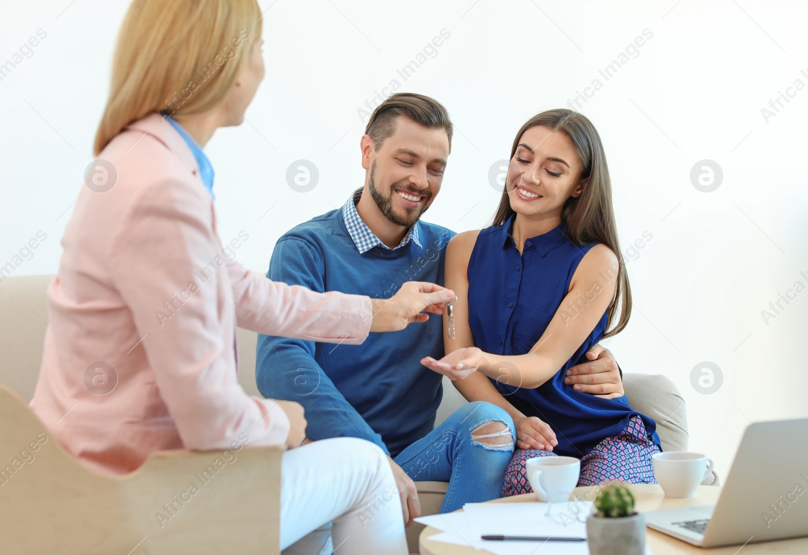 Photo of Female real estate agent giving house key to couple in office